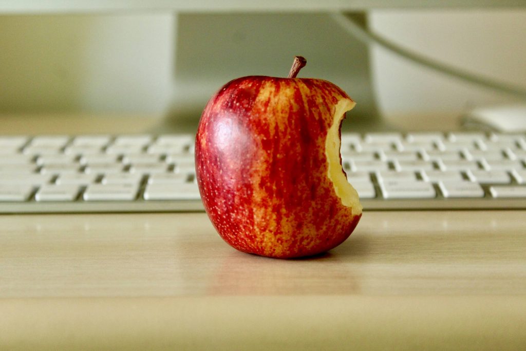 Red apple placed in front of a computer keyboard, symbolizing learning and education